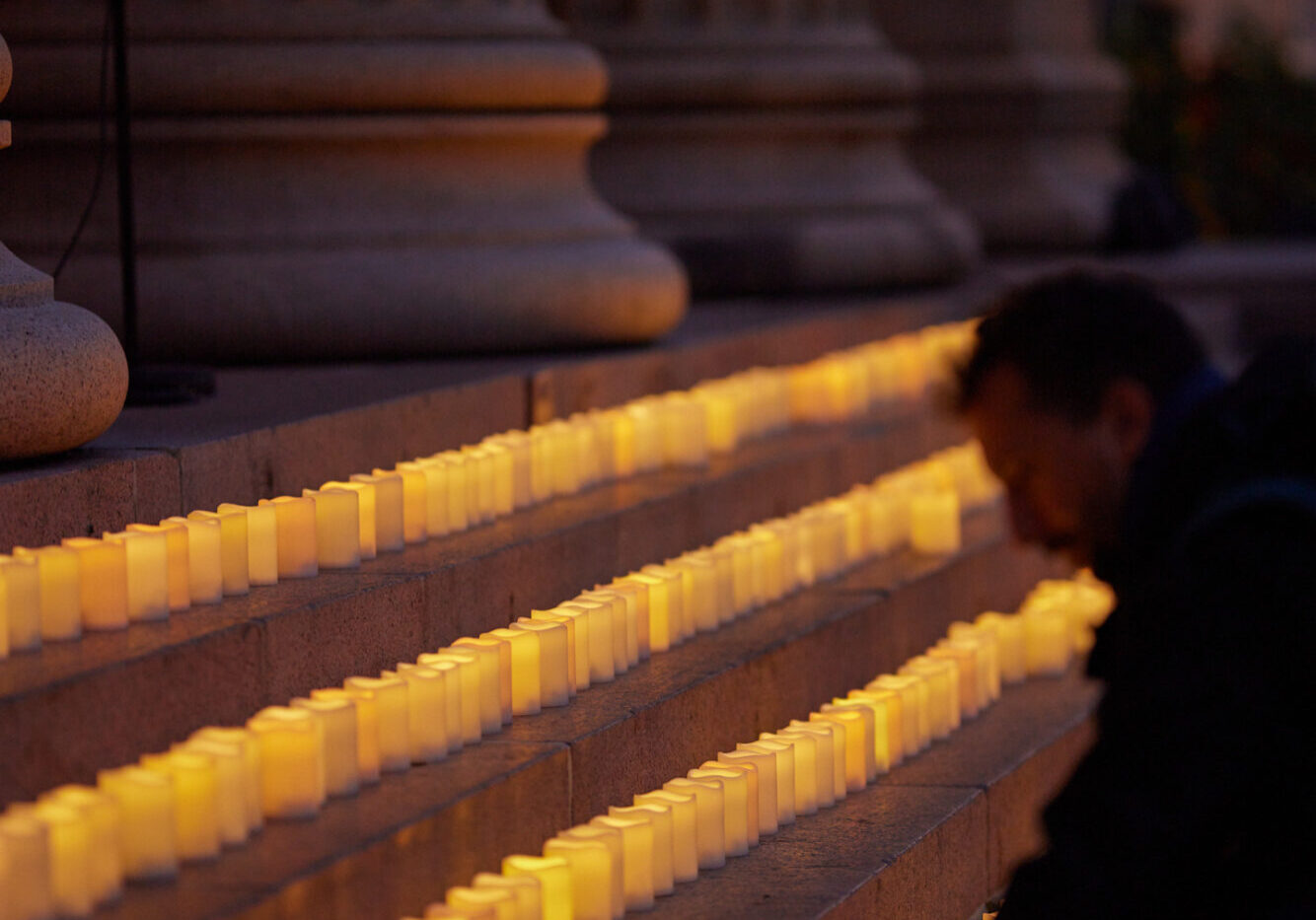 En mann tenner et lys, sammen med 600 for å minnes de som tok livet sitt forrige år.